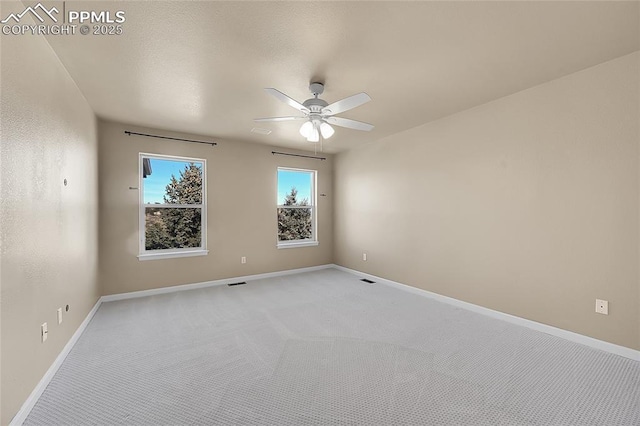 spare room featuring light carpet, ceiling fan, and baseboards