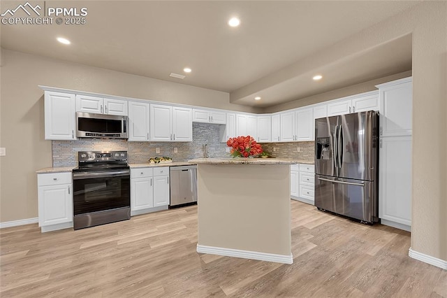 kitchen featuring stainless steel appliances, tasteful backsplash, light wood-style flooring, and white cabinets