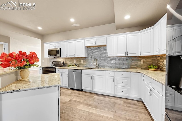 kitchen featuring light wood-type flooring, white cabinetry, appliances with stainless steel finishes, and a sink