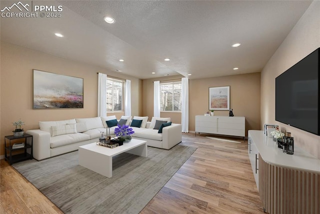 living area with recessed lighting, a textured ceiling, and light wood finished floors