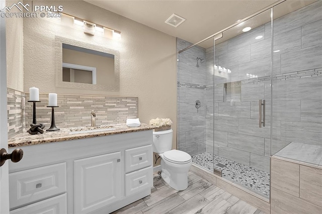 bathroom featuring visible vents, backsplash, toilet, a shower stall, and vanity