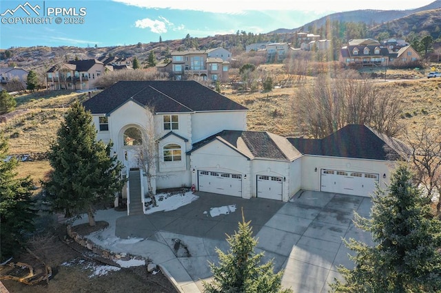 view of front of property featuring stucco siding, a mountain view, a garage, a residential view, and driveway