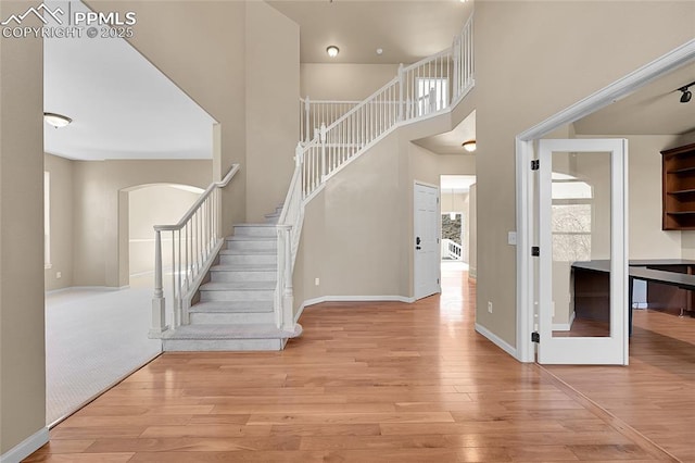 entryway featuring stairs, a high ceiling, wood finished floors, and baseboards