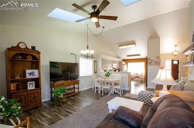 living area with a wealth of natural light, ceiling fan with notable chandelier, lofted ceiling with skylight, and dark wood-type flooring