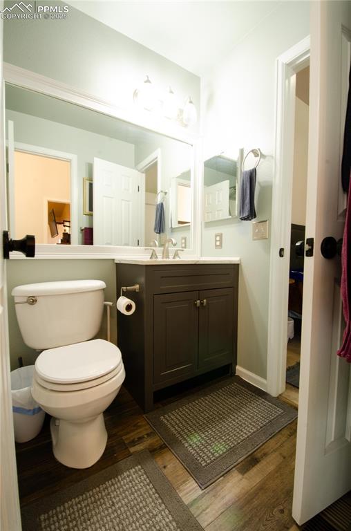 bathroom featuring toilet, wood finished floors, and vanity