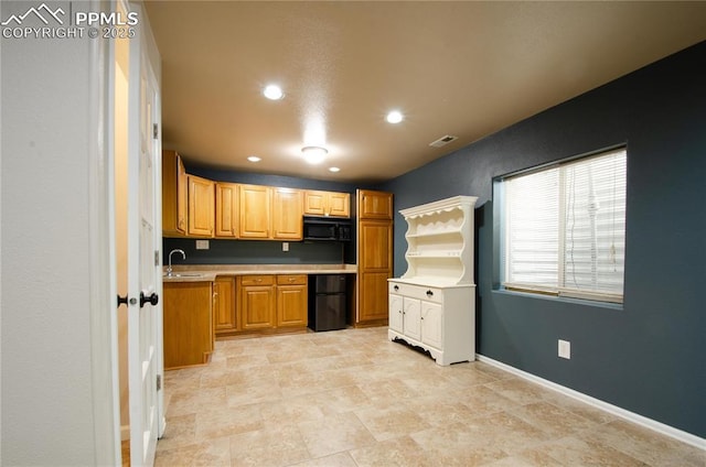 kitchen with visible vents, baseboards, light countertops, black appliances, and a sink