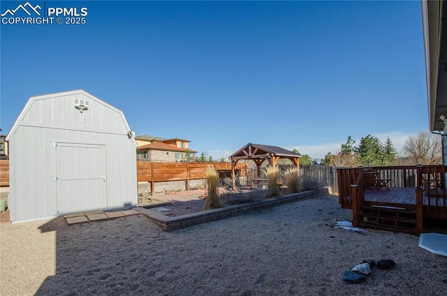 view of yard featuring fence, a wooden deck, a gazebo, an outbuilding, and a storage unit