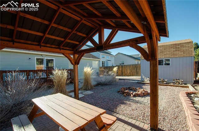 view of patio / terrace with fence, a shed, an outdoor fire pit, a gazebo, and an outbuilding