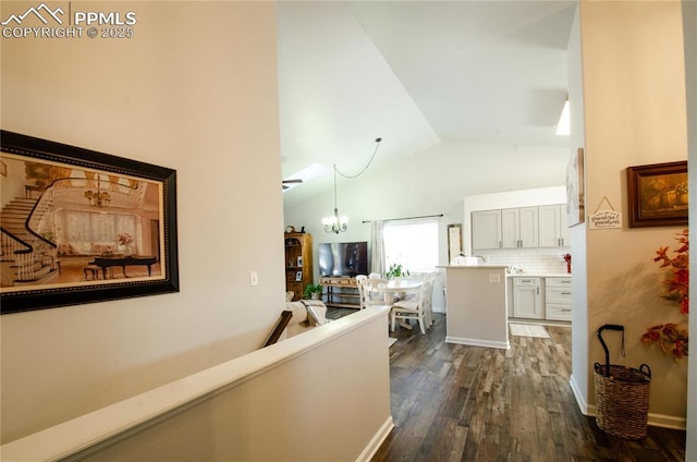 hall featuring baseboards, an upstairs landing, dark wood-style floors, a notable chandelier, and high vaulted ceiling