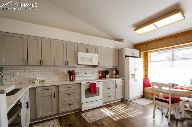 kitchen with backsplash, dark wood finished floors, vaulted ceiling, white appliances, and a sink