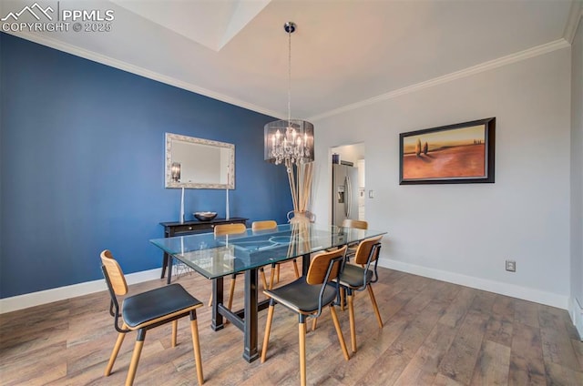 dining area featuring a notable chandelier, crown molding, baseboards, and wood finished floors