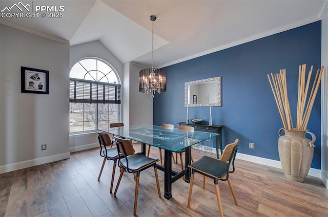 dining area with crown molding, vaulted ceiling, wood finished floors, a chandelier, and baseboards