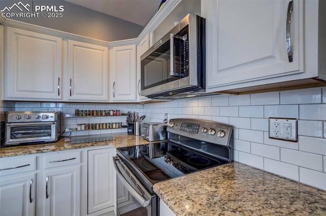 kitchen with appliances with stainless steel finishes, a toaster, white cabinetry, and tasteful backsplash