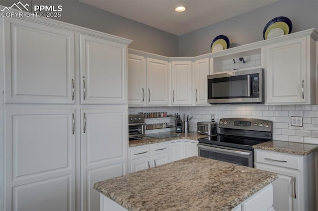 kitchen with appliances with stainless steel finishes, white cabinets, decorative backsplash, and light stone countertops