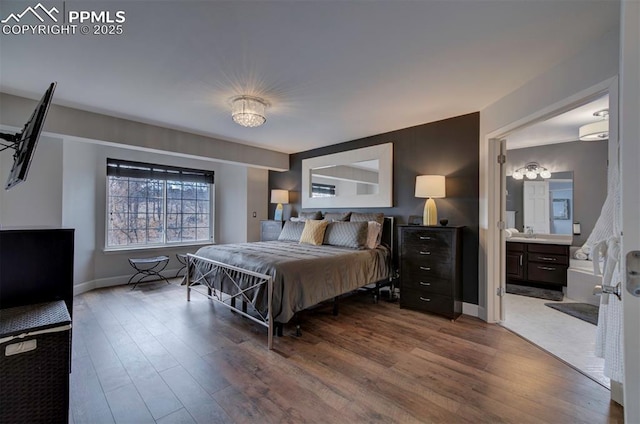 bedroom with a sink, ensuite bathroom, wood finished floors, and baseboards