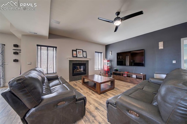 living room with a fireplace, wood finished floors, visible vents, and a ceiling fan