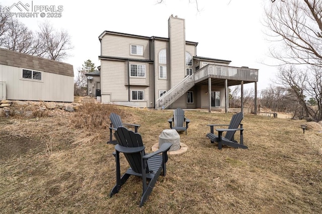 back of property with an outbuilding, an outdoor fire pit, stairs, a wooden deck, and a chimney