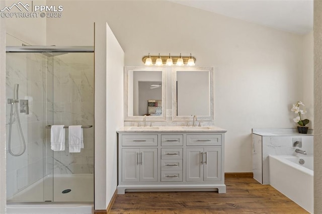 full bath with double vanity, wood finished floors, a sink, and a marble finish shower