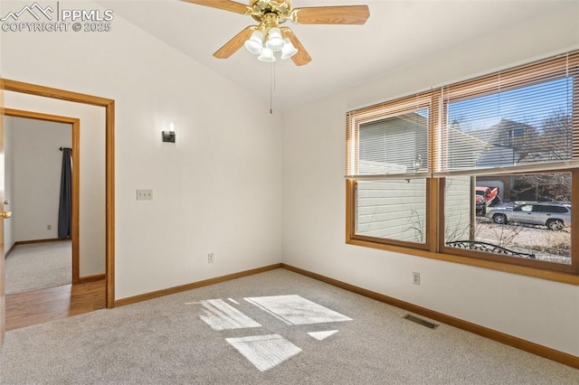 carpeted spare room featuring lofted ceiling, baseboards, and visible vents