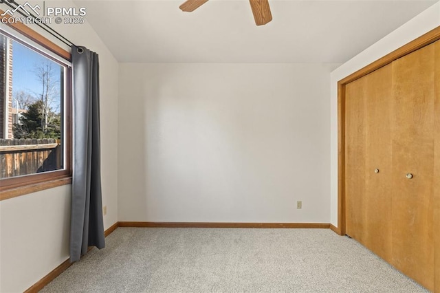 unfurnished bedroom with a closet, carpet flooring, ceiling fan, and baseboards