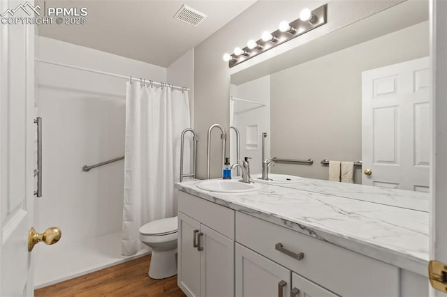 bathroom with visible vents, toilet, wood finished floors, curtained shower, and vanity