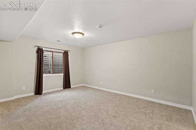 spare room featuring light colored carpet and baseboards