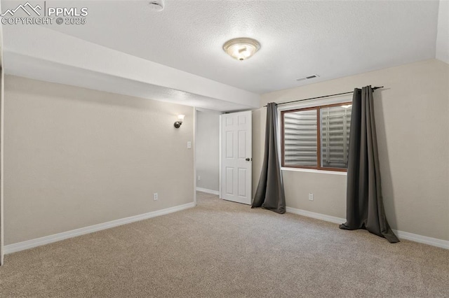 carpeted empty room with a textured ceiling and baseboards