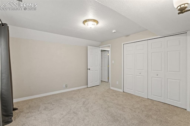 unfurnished bedroom featuring carpet floors, lofted ceiling, a closet, a textured ceiling, and baseboards