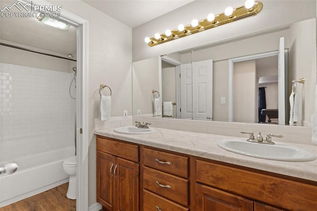 full bath featuring shower / bathtub combination, double vanity, wood finished floors, and a sink