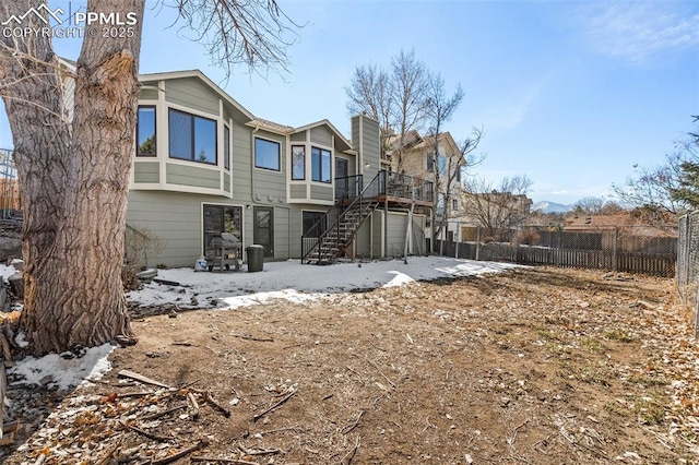 back of property with a deck, stairway, and fence