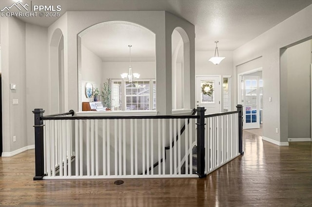 hall featuring baseboards, an upstairs landing, a healthy amount of sunlight, and wood finished floors