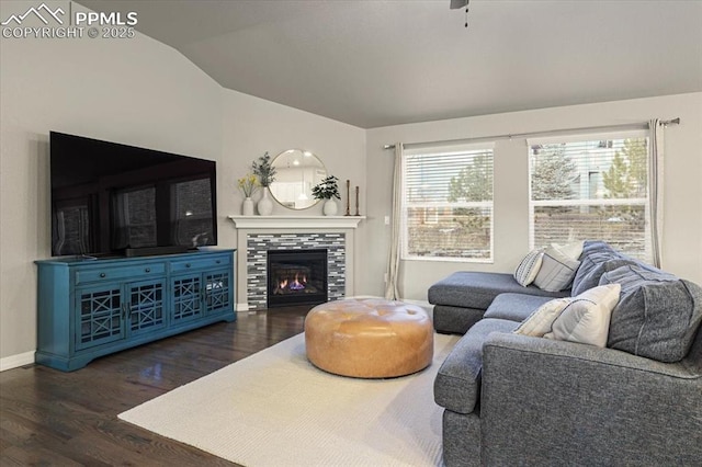 living area with a wealth of natural light, lofted ceiling, wood finished floors, and a tiled fireplace