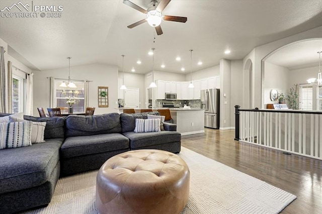 living room featuring light wood-style flooring, ceiling fan with notable chandelier, recessed lighting, arched walkways, and lofted ceiling