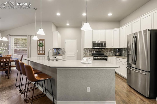 kitchen featuring dark wood-style floors, a sink, appliances with stainless steel finishes, white cabinetry, and tasteful backsplash