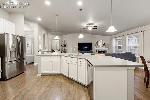 kitchen featuring light wood-style flooring, a sink, light countertops, stainless steel fridge, and open floor plan