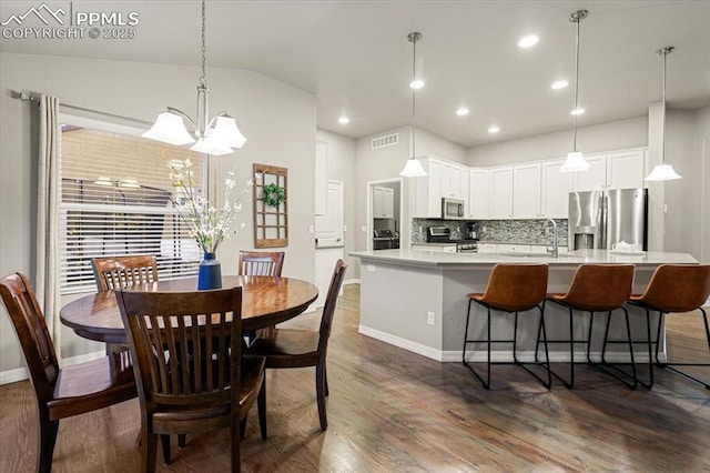 dining space with visible vents, dark wood finished floors, and vaulted ceiling