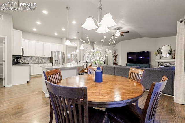 dining room with vaulted ceiling, recessed lighting, light wood-type flooring, and ceiling fan