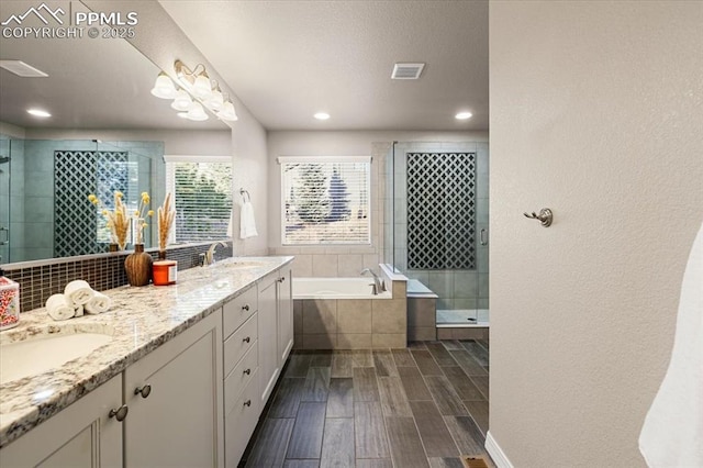 bathroom featuring visible vents, wood finish floors, double vanity, a stall shower, and a bath