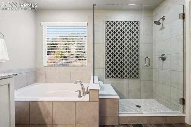 bathroom with a stall shower, a bath, and vanity