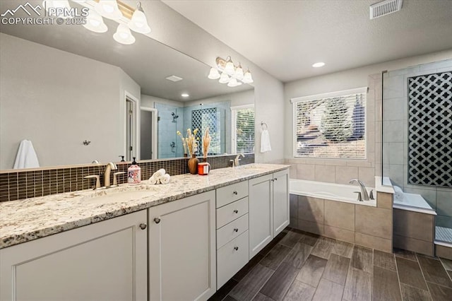 bathroom featuring a stall shower, a bath, visible vents, and a sink