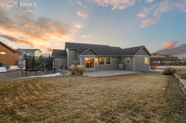 back of house featuring a patio area, central AC unit, a lawn, and a trampoline