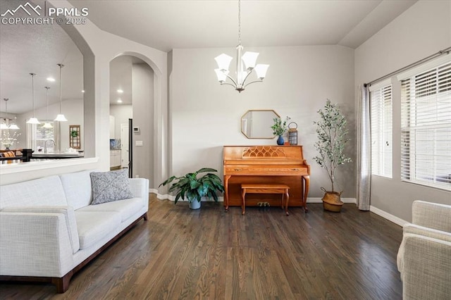 interior space featuring arched walkways, a chandelier, dark wood-type flooring, and baseboards