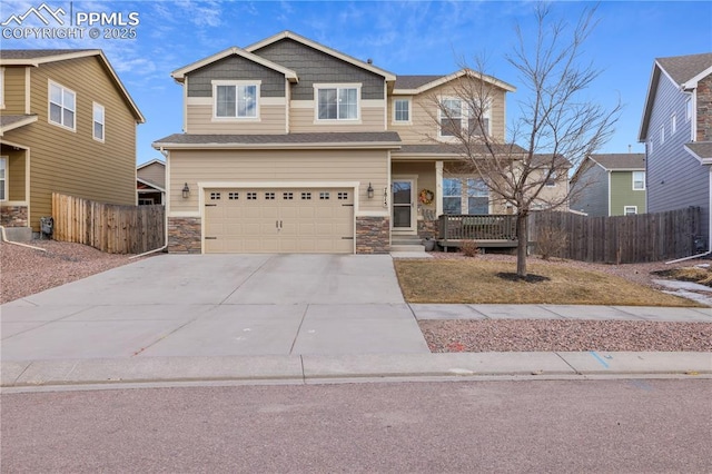 craftsman house with driveway, stone siding, a garage, and fence