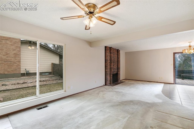 spare room with a brick fireplace, visible vents, a textured ceiling, and carpet flooring