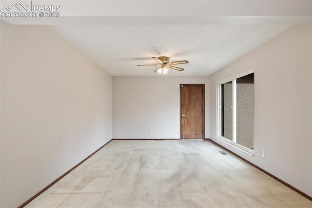 empty room featuring a ceiling fan, baseboards, a textured ceiling, and light colored carpet