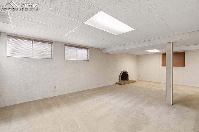 basement with carpet floors, a fireplace, and a paneled ceiling