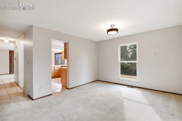 unfurnished room featuring visible vents, a textured ceiling, and light colored carpet