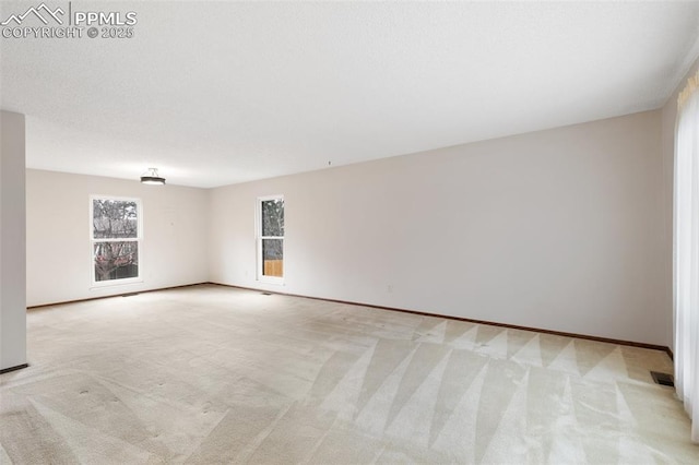 spare room featuring light colored carpet and baseboards