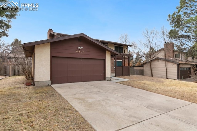 view of front facade featuring a garage, fence, driveway, a front lawn, and a chimney