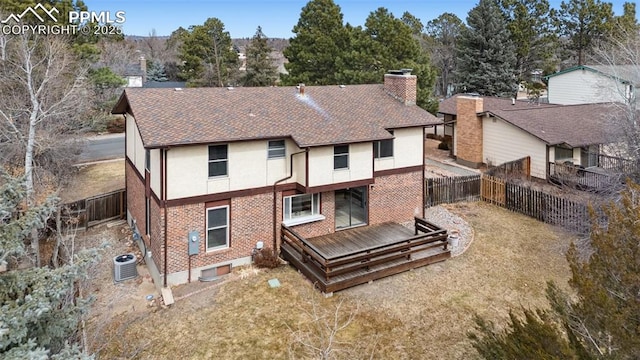 rear view of house with a fenced backyard, a chimney, a wooden deck, central air condition unit, and brick siding